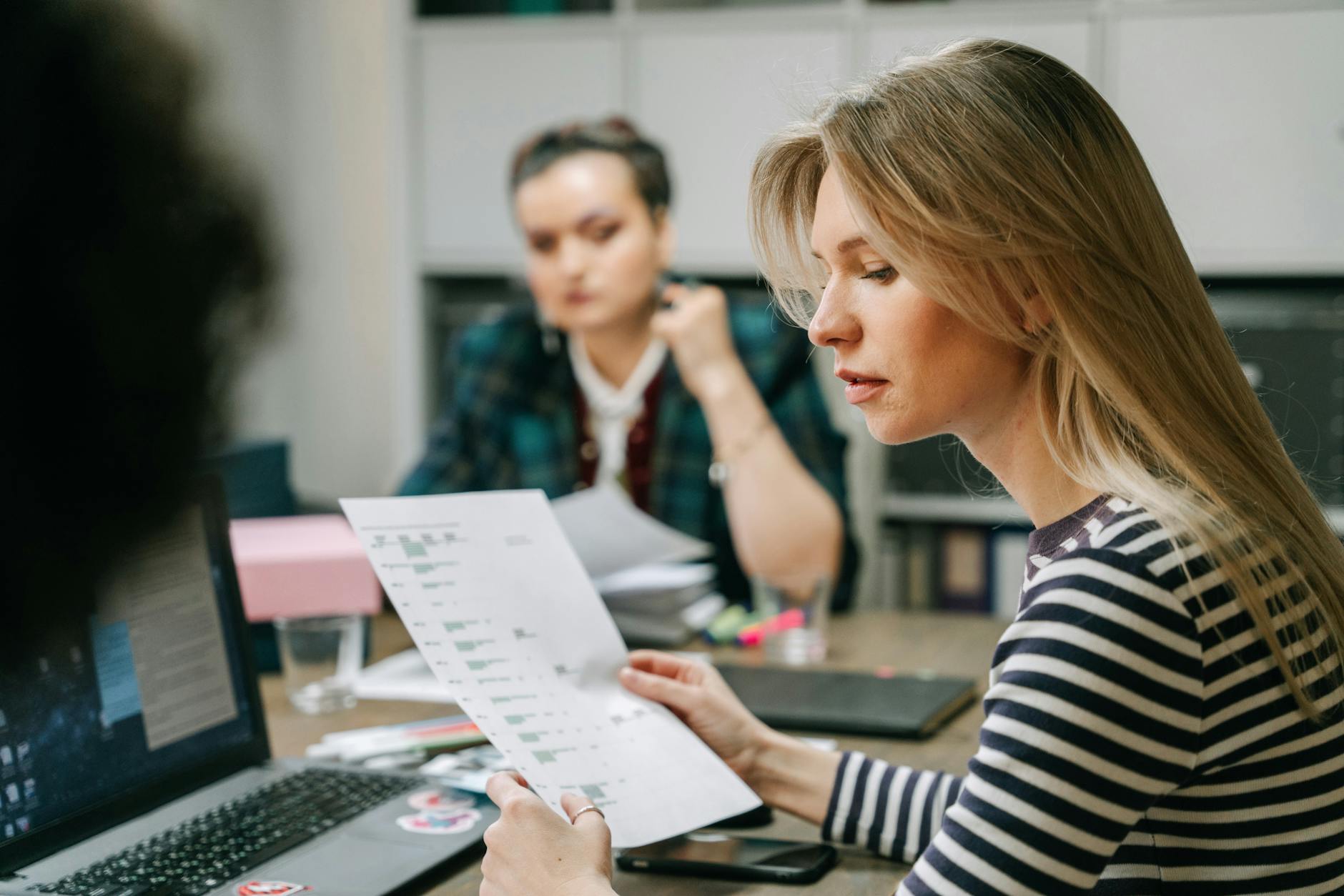A woman reviews documents during a business planning meeting in a modern office setting.